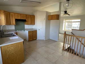 Kitchen featuring vaulted ceiling, sink, light tile patterned floors, and ceiling fan