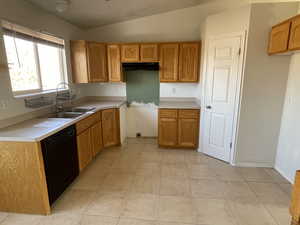 Kitchen featuring light tile patterned flooring, vaulted ceiling, dishwasher, and sink