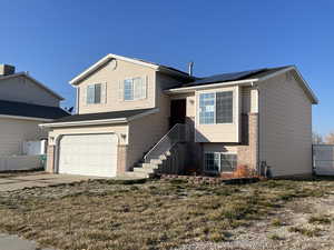 Split level home featuring a garage and solar panels