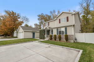 View of front of property with a garage, an outdoor structure, and a front yard