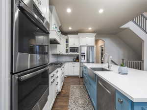 Kitchen with blue cabinetry, sink, white cabinetry, stainless steel appliances, and a kitchen island with sink