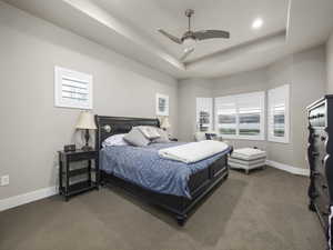 Carpeted bedroom with a raised ceiling and ceiling fan