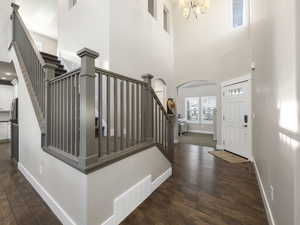 Foyer entrance featuring a high ceiling, dark wood-type flooring, and a chandelier