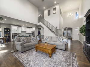 Living room with dark wood-type flooring, sink, a chandelier, and a towering ceiling