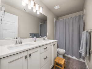 Full bathroom with vanity, shower / tub combo with curtain, a textured ceiling, and toilet