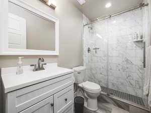 Bathroom featuring vanity, a tile shower, and toilet