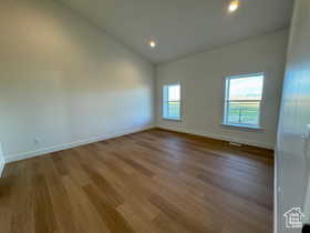 Spare room with hardwood / wood-style flooring and high vaulted ceiling