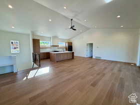 Unfurnished living room featuring ceiling fan, lofted ceiling, and light wood-type flooring