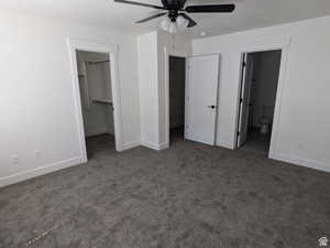 Unfurnished bedroom featuring connected bathroom, a walk in closet, a textured ceiling, dark carpet, and a closet