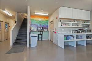 Kitchen with a textured ceiling, concrete flooring, and white cabinets
