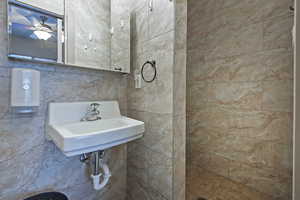 Bathroom with tile walls, sink, tasteful backsplash, and tiled shower