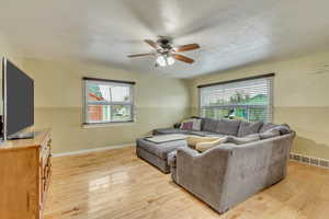 Living room featuring a wealth of natural light, ceiling fan, and light wood-type flooring