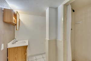 Bathroom featuring vanity, a textured ceiling, and walk in shower