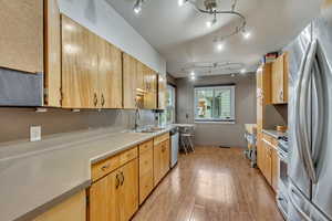 Kitchen with appliances with stainless steel finishes, light hardwood / wood-style floors, and sink