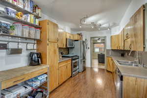 Kitchen featuring sink, backsplash, ceiling fan, light hardwood / wood-style floors, and stainless steel appliances