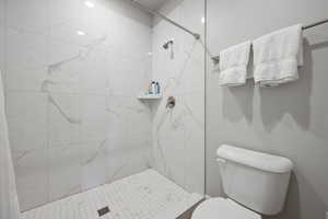 Bathroom featuring a tile shower and toilet