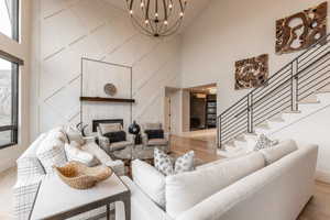 Living room featuring light wood-type flooring, a notable chandelier, and high vaulted ceiling