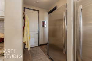 Hallway to pantry. Full refrigerator and full freezer with wood look tile flooring