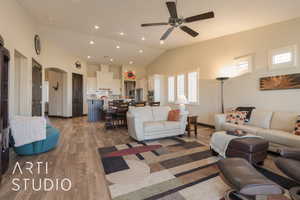 Great room featuring ceiling fan, lofted ceiling, and wood look tile flooring