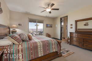 Master bedroom featuring access to outside, light colored carpet, and ceiling fan