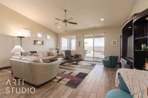 Living room featuring vaulted ceiling, wood look tile floors and a ceiling fan