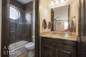 Full casita bathroom featuring ceiling fan, enclosed tub / shower combo, vanity, and toilet