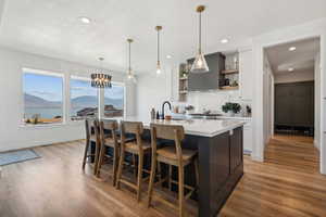 Kitchen featuring decorative light fixtures, a water and mountain view, white cabinets, a kitchen island with sink, and light hardwood / wood-style floors