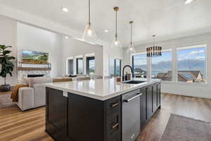 Kitchen featuring a mountain view, decorative light fixtures, an island with sink, and dishwasher