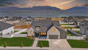 Modern farmhouse style home featuring a water and mountain view and a lawn