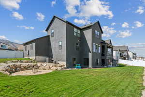 Back of property with a patio area, a lawn, and central air condition unit