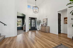 Foyer with an inviting chandelier, hardwood / wood-style flooring, and a towering ceiling