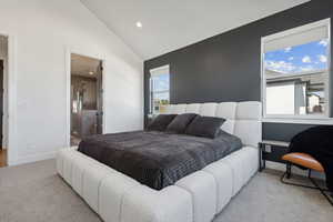 Carpeted bedroom featuring lofted ceiling and connected bathroom