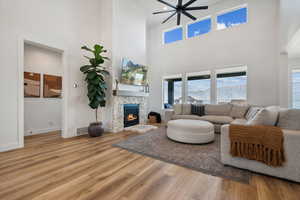 Living room with hardwood / wood-style flooring, a towering ceiling, and a fireplace