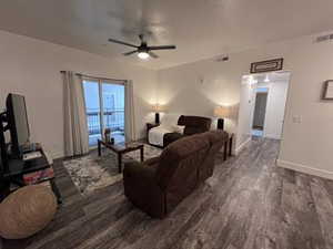 Living room with dark hardwood / wood-style floors and ceiling fan