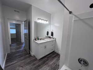 Bathroom with vanity, hardwood / wood-style flooring, and shower / bathtub combination