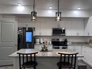 Kitchen with hanging light fixtures, a breakfast bar area, stainless steel appliances, and a kitchen island