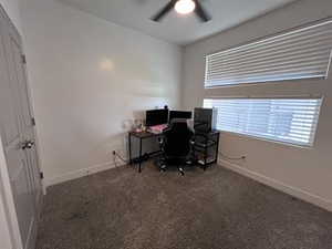 Office area featuring ceiling fan and dark carpet