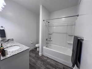 Full bathroom featuring hardwood / wood-style flooring, shower / washtub combination, vanity, and toilet