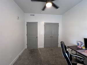 Office area with ceiling fan and dark carpet