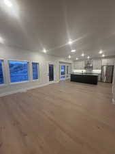 Unfurnished living room featuring sink and light hardwood / wood-style flooring