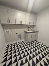 Laundry area featuring washer hookup, sink, cabinets, and electric dryer hookup