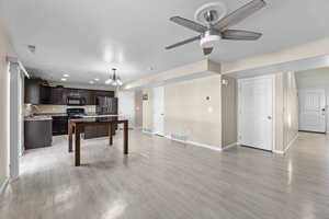 Rec room with ceiling fan with notable chandelier, sink, and light wood-type flooring