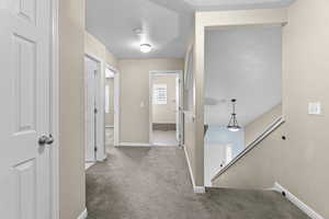 Hall with carpet floors and a textured ceiling