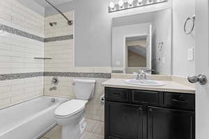 Full bathroom featuring vanity, tiled shower / bath, tile walls, and toilet