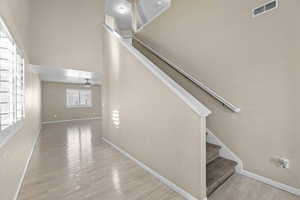 Staircase featuring hardwood / wood-style floors, a towering ceiling, and ceiling fan