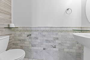 Bathroom featuring tile walls and toilet