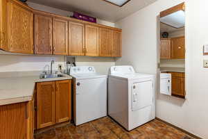 Laundry room with sink, washer and clothes dryer, cabinets, and a textured ceiling