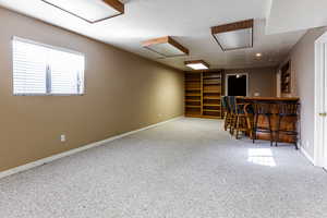 Interior space featuring indoor bar, carpet, and a textured ceiling