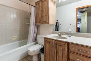 Full bathroom with vanity, toilet, shower / bath combo, tile patterned floors, and a textured ceiling