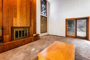 Unfurnished living room with a towering ceiling, a healthy amount of sunlight, and carpet